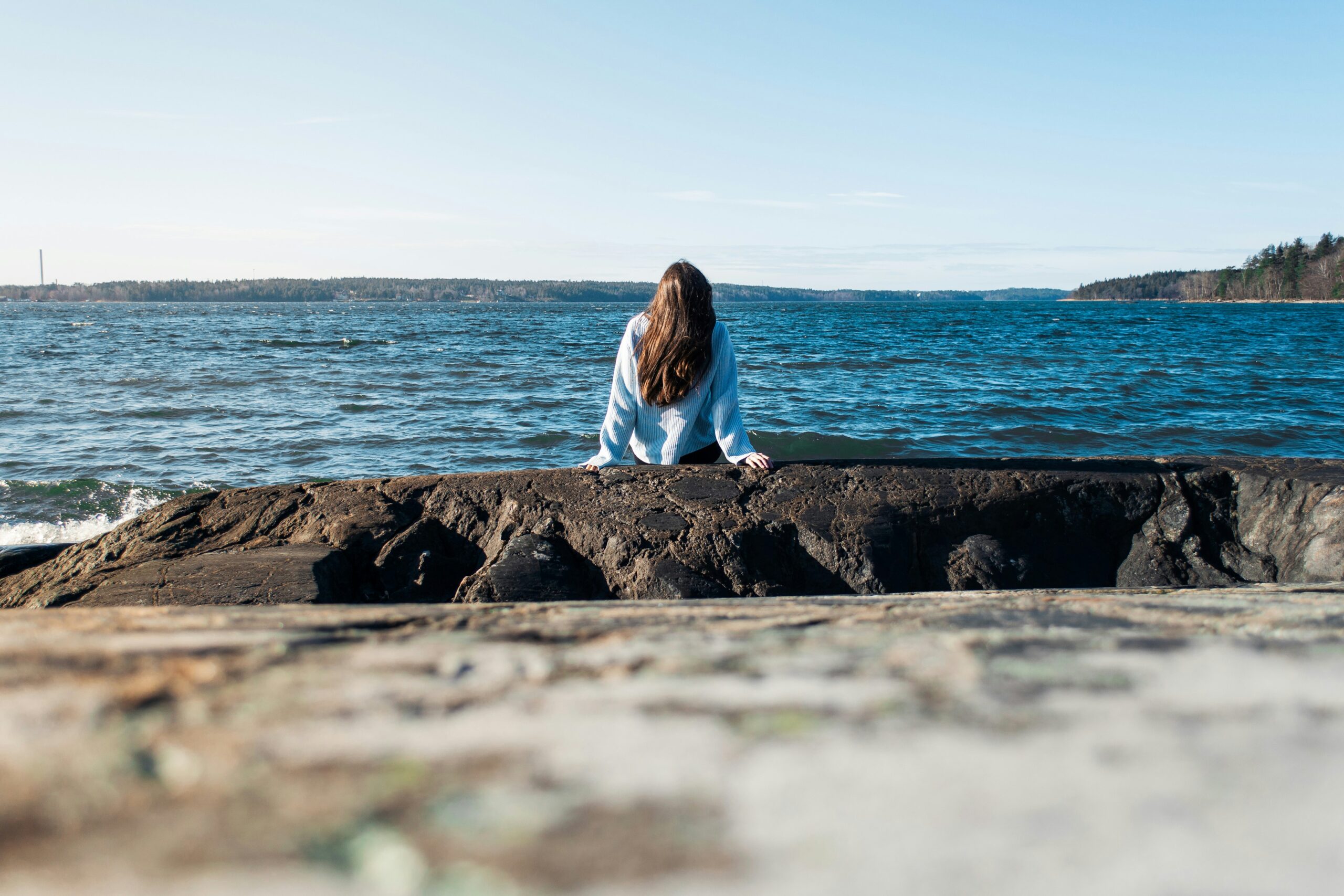 Mehrere Frauen sitzen entspannt am Strand der Ostsee und schauen aufs Meer